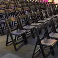 A row of black padded folding chairs in a room available for hire.