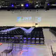A spacious room with tables and chairs set up for an event, including black padded folding chair hire options.