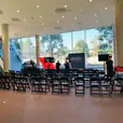 A room full of black padded folding chairs in a room with large windows.