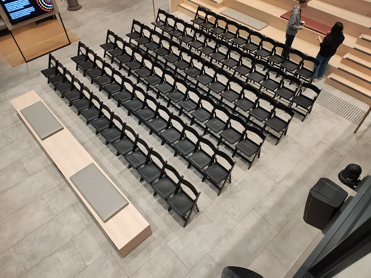 Rows of black padded folding chairs arranged theatre-style for a conference or presentation event in a modern venue