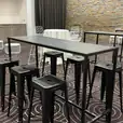 A room with a black rectangular table and stools in it.