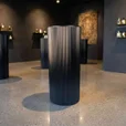 Black ripple metal plinth used as a display pedestal in an interior setting