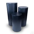 Three black ripple metal plinths with round tops and fluted sides in graduated heights