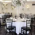 A black and white room with tables and Black Tiffany Chair Hire.