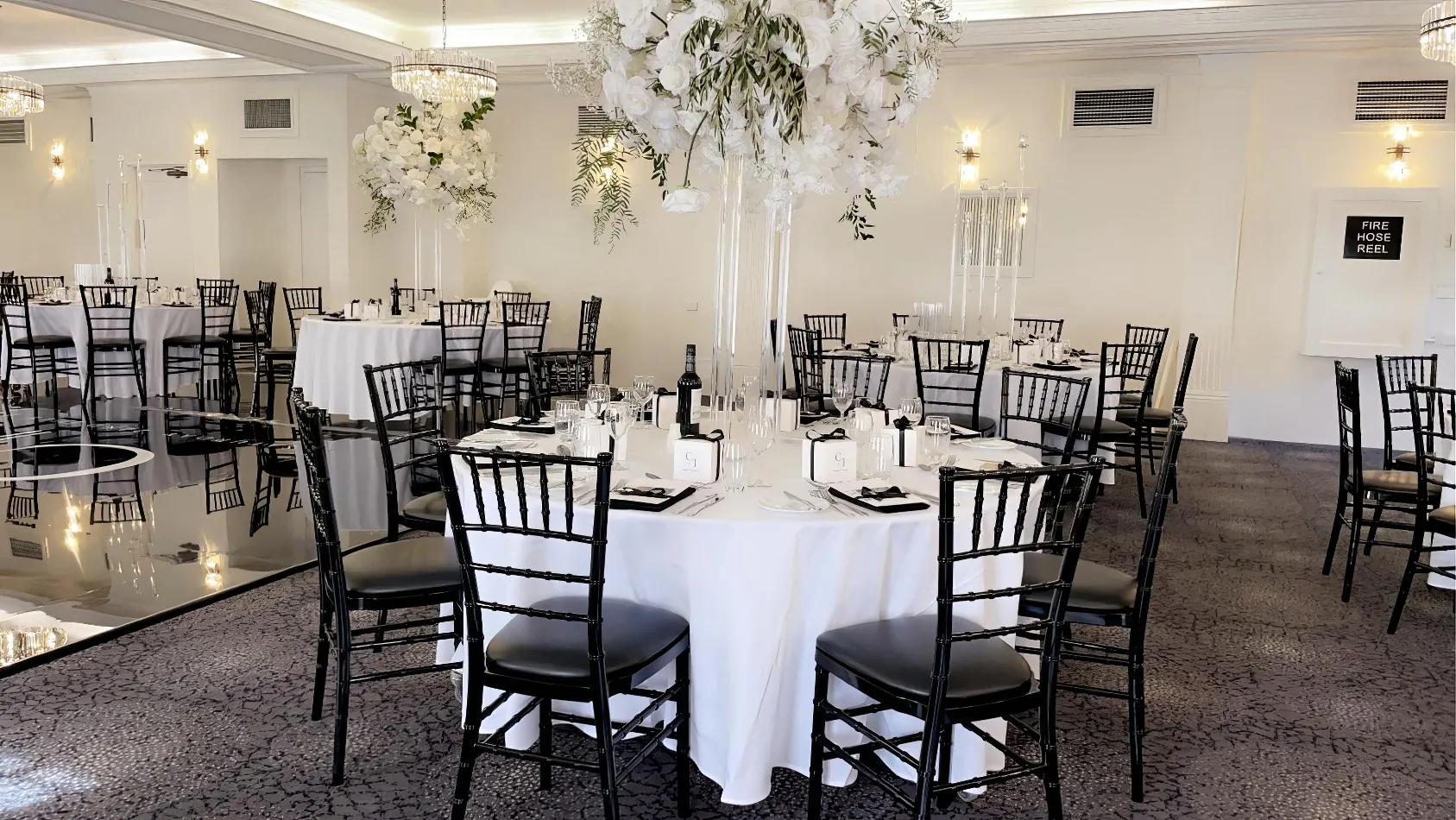 A black and white room with tables and Black Tiffany Chair Hire.