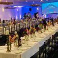 A large room with tables and chairs set up for an event, featuring Black Tiffany Chair Hire.
