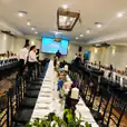 A long table is set up in a large room for a sophisticated event with black Tiffany chair hire available.