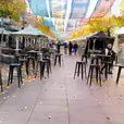 A city street adorned with tables and chairs, available for Black Tolix Stool Hire.