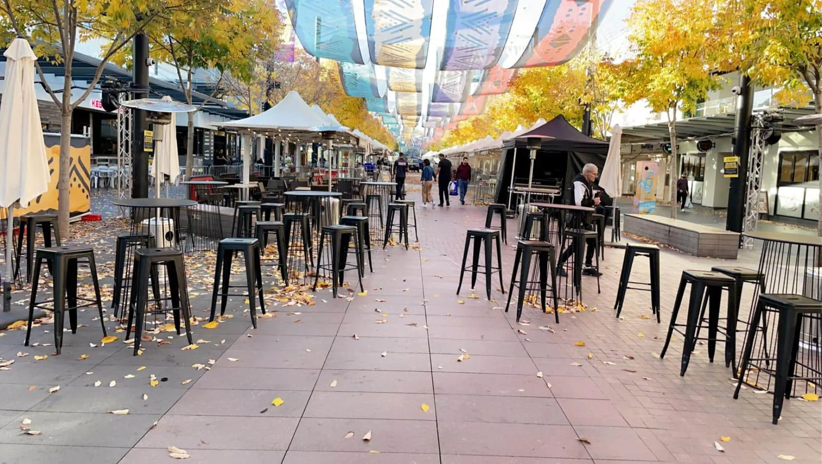 A city street adorned with tables and chairs, available for Black Tolix Stool Hire.