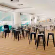 A spacious room adorned with an assortment of tables and chairs, including sleek black Tolix stool hire options.