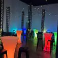 A room filled with colorful lights, stools, and Black Tolix Stool Hire.