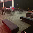 Black velvet bench seating combined with wire bar furniture and cocktail tables inside a large premium event venue with ambient lighting