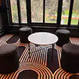 Black velvet cylinder stools arranged around a white coffee table in a modern lounge setting beside large feature windows