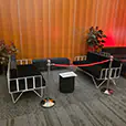 Black velvet lounge seating with white frame sofas, ottoman bench seating, rope barriers and indoor plants in a VIP event area