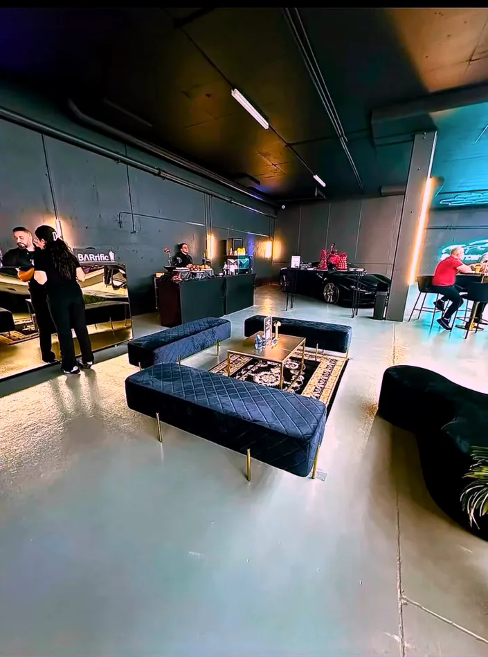 Black velvet ottoman benches arranged in an L around a gold coffee table and black and gold rug in a car showroom.