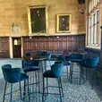 Black velvet ottoman stools beside a bar table at an event