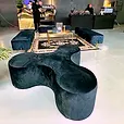 Black velvet ottoman benches framing a black and gold rug in a warehouse event space.
