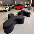 Two black velvet Apollo tripod daybeds arranged as feature seating in a supercar showroom.
