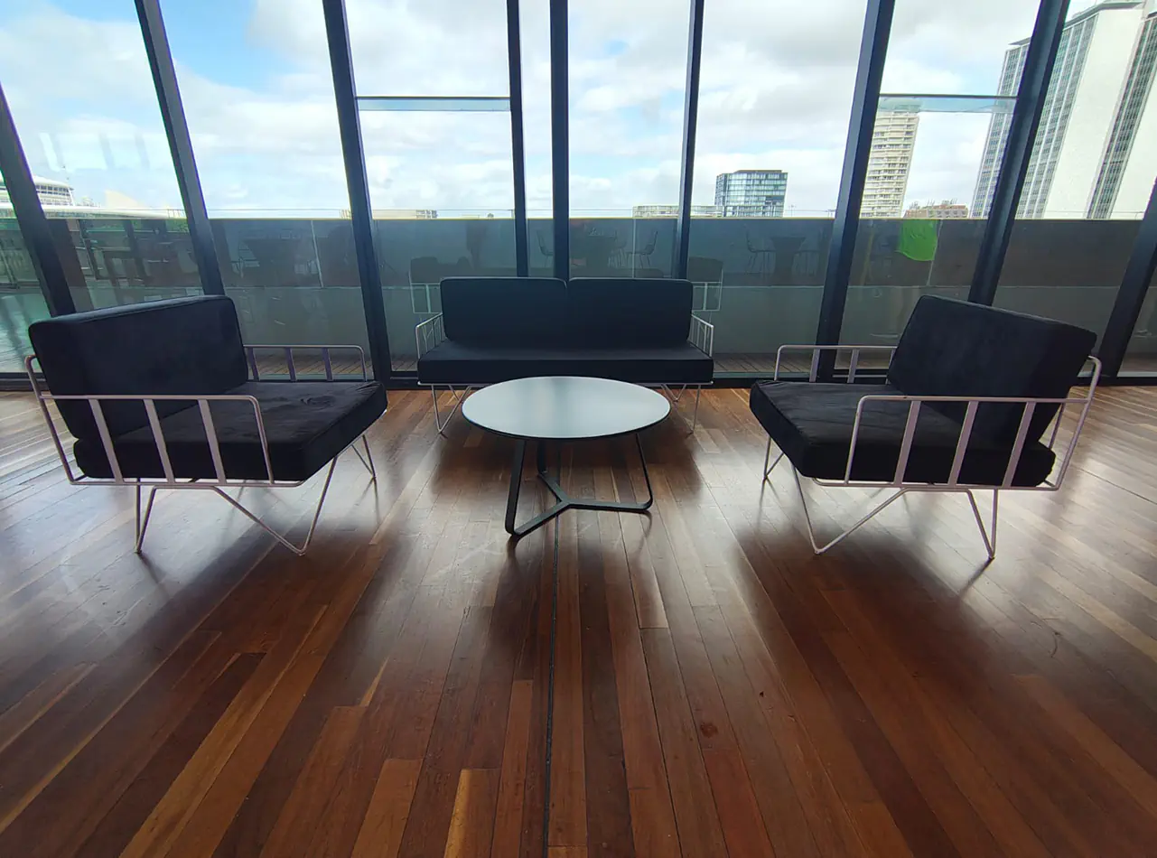Black velvet wire lounge chairs with matching sofa and round coffee table positioned beside floor-to-ceiling windows in a modern venue