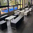 Modern lounge seating setup with black and white ottoman cubes, low tables and bench seating arranged along large windows in an indoor event space