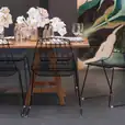 A dining table with black chairs and a painting on the wall. Black Arrow Chair Hire.