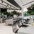 A black table setting in a restaurant featuring a black wire chair for hire.