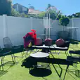 A backyard with black furniture and a white fence, featuring Black Wire Chair.