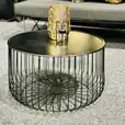 A black wire coffee table with a gold vase.