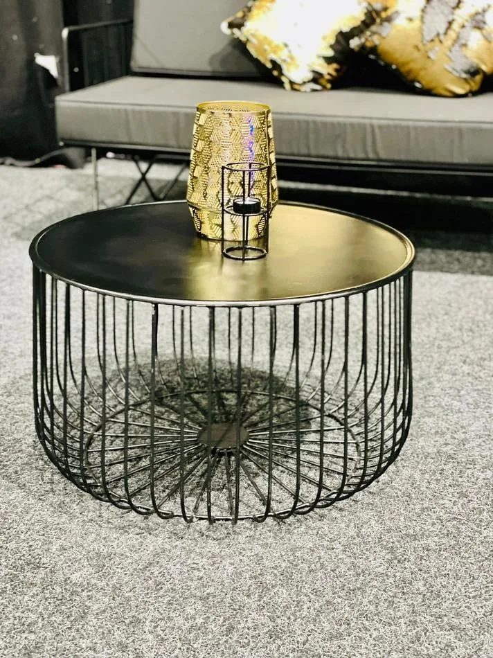A black wire coffee table with a gold vase.