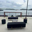 Black wire coffee table with velvet ottoman benches and cylinder stools in an outdoor harbourfront lounge setting