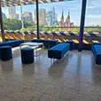 Blue velvet ottoman bench seating with matching stools and sofas in a modern event lounge overlooking the Sydney skyline