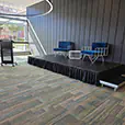 Blue velvet wire armchairs with white wire coffee table displayed on a small presentation stage beside a lectern in a conference venue