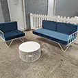 Blue velvet wire lounge chair and sofa set with white wire coffee table arranged in an indoor event space beside white picket fencing