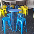 Blue wire cocktail table with matching stools used in an indoor event setup with multiple tables arranged across the venue