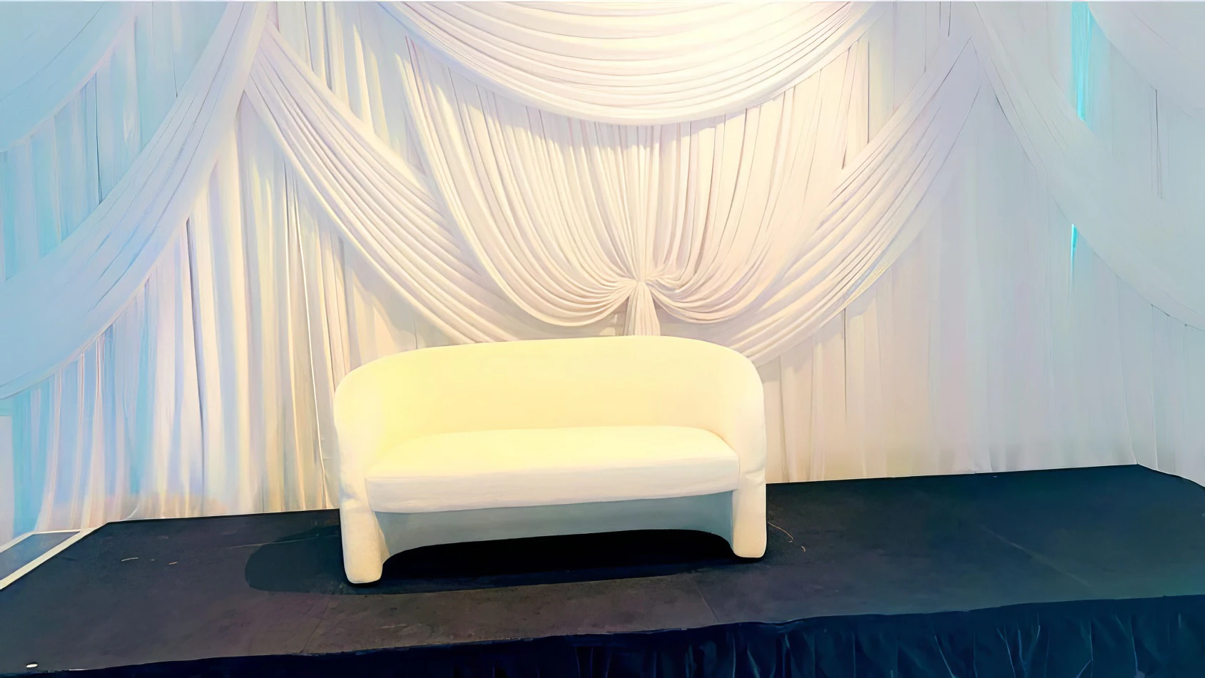 A white bouclé 2 seater sofa in front of a white backdrop.