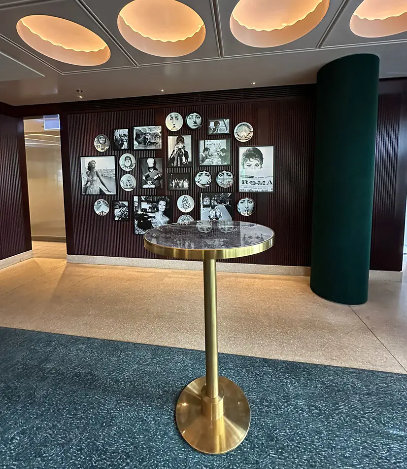 Brass cocktail table with blue marble top positioned in a stylish indoor venue with decorative wall art, timber panelling, and modern ceiling lighting