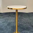 A brass cocktail bar table hire with a white top.