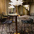 Brass cocktail tables with black tops arranged in a lounge-style event space with upholstered seating, wall lighting and decorative interior finishes
