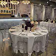 Elegant wedding reception table setting with clear Victorian chairs, white table linen, floral centrepieces and ambient chandelier lighting