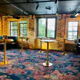 A room with tables and chairs in a brick building, featuring Brass Cocktail Bar Tables with Black Marble Tops.