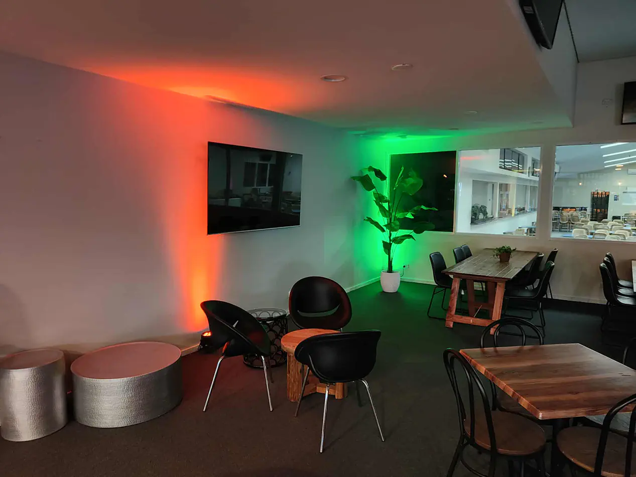 Indoor function venue with colour-changing uplighting creating ambient red and green lighting effects on the walls