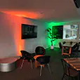 Indoor function venue with colour-changing uplighting creating ambient red and green lighting effects on the walls