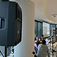 Indoor conference setup with speakers on stands, microphones and presentation screen during a formal event in a modern venue