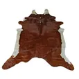 Tan and white cow hide rug with natural irregular shape