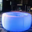 A blue LED circular table sitting on a carpeted floor, available for curved glow bar hire.