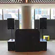 DJ booth with PA speakers on stands in modern indoor venue with city skyline windows and lounge seating