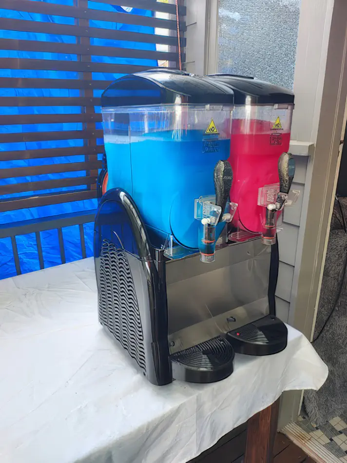 Double slushie machine with blue and red frozen drinks ready to serve on a tabletop setup for events and parties