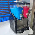 Double slushie machine with blue and red frozen drinks ready to serve on a tabletop setup for events and parties
