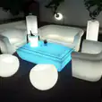 A living room with a white double seater sofa, chairs, and a glow lamp.