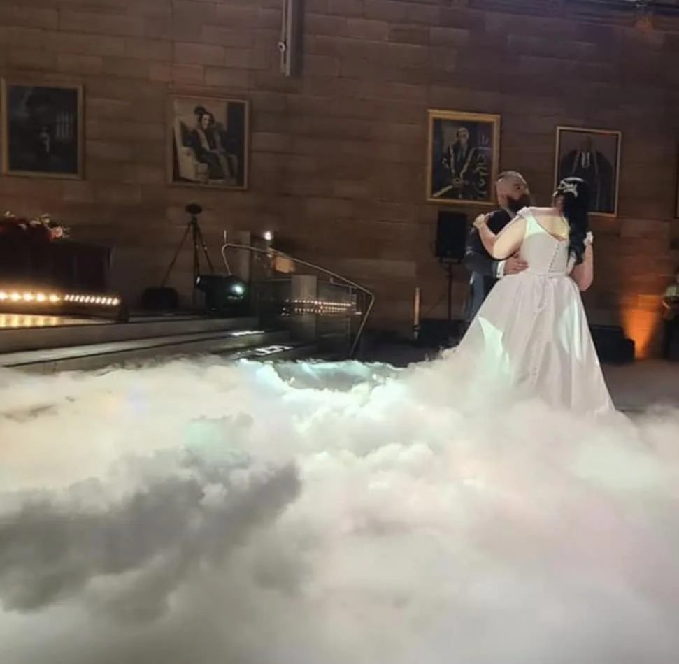 A bride and groom standing on a cloud in a room, enhanced with the mystical ambiance created by a dry ice machine.